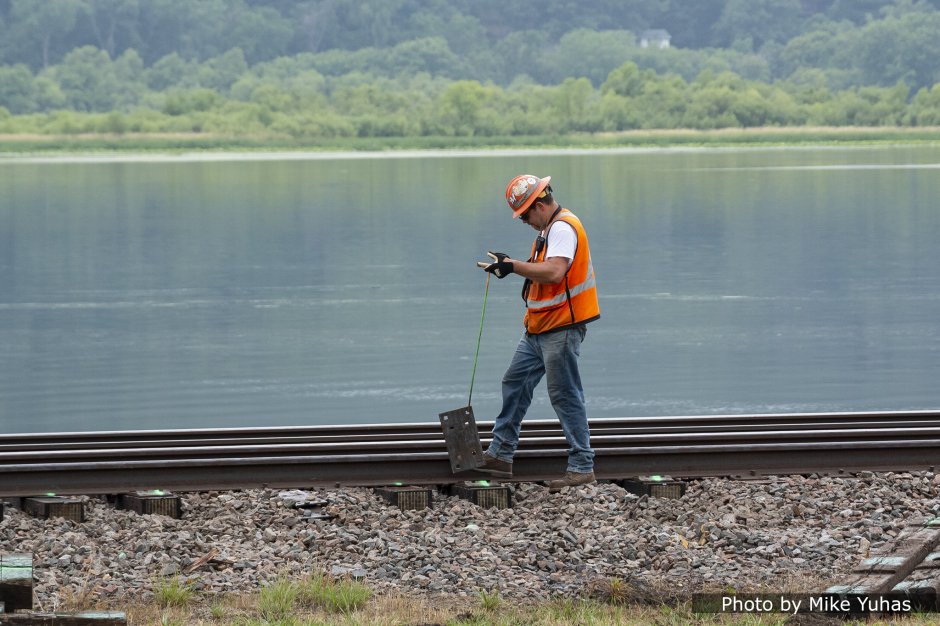 Workers pick up the tie plates and manually place them on the tie ends.